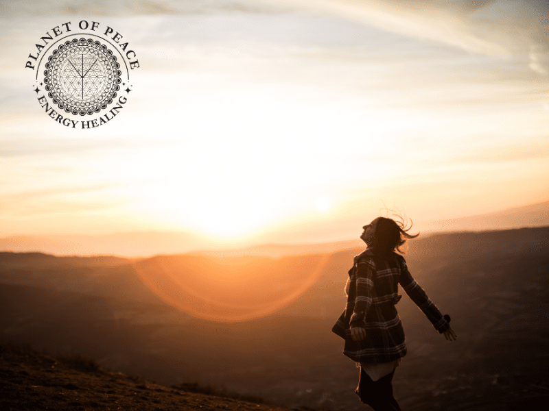 Person standing barefoot on earth with arms open to the rising sun, symbolizing emotional release and healing. Gentle golden light flows toward their heart, representing openness and inner peace.