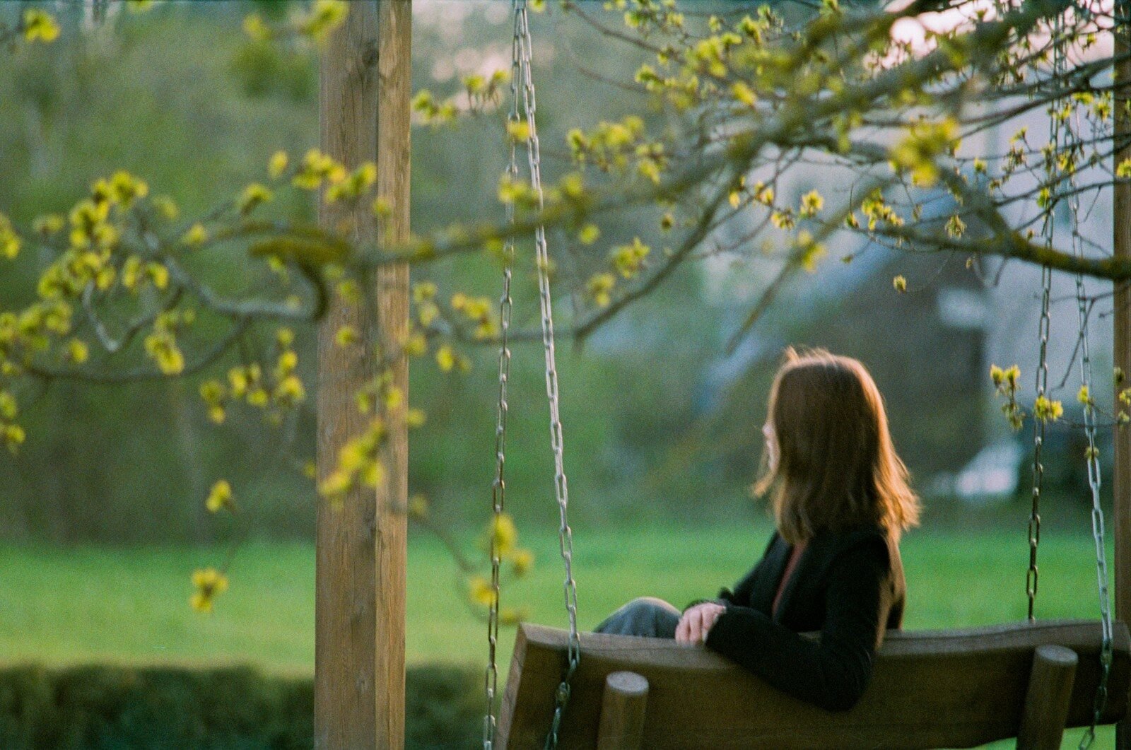 Young woman sitting on a swing in a sunny garden