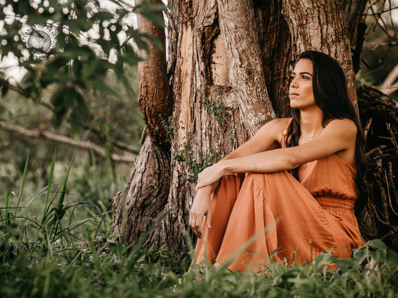 Woman sitting peacefully in nature, releasing emotional tension through meditation